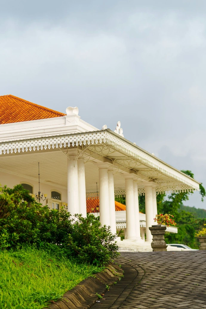 A white building with columns and a red roof